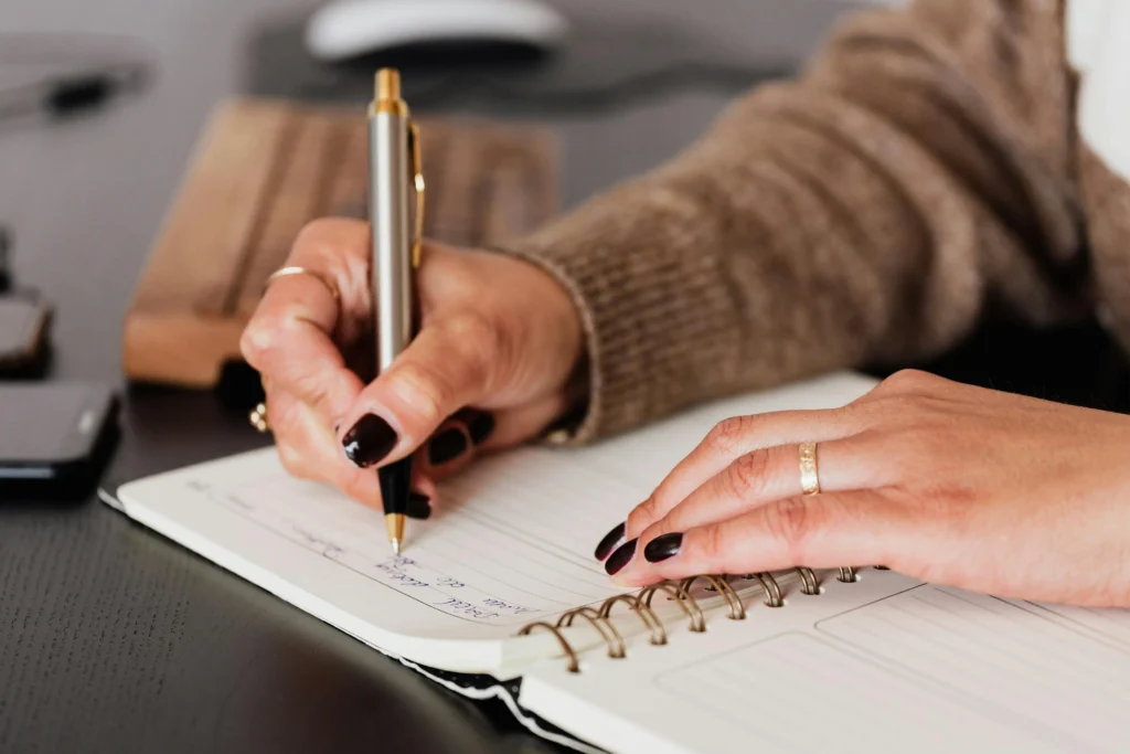 Mulher escrevendo em seu caderno, cultivando o hábito de uma vida simples